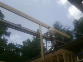 Carpenter setting a ridge beam over a new addition frame — Ice Dam Removal by Roofing Brothers in Red Creek