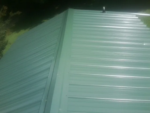 New green metal panels meeting at the ridge of a roof — Flat Roof Repair work by our crew in Red Creek