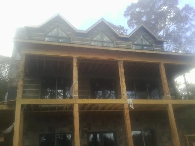 Dormers and porch framing on a large log home under construction — Roof Coating work by our crew in Red Creek