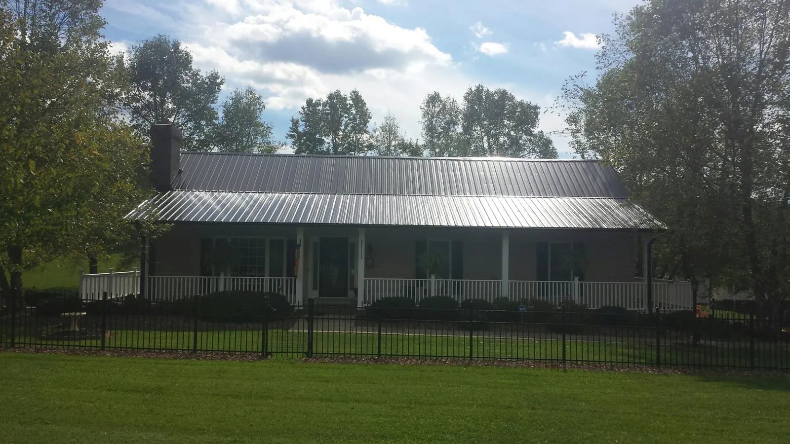 Gray metal roof on a brick ranch with a full width front porch — Gutter Guard Installation work by our crew in Red Creek