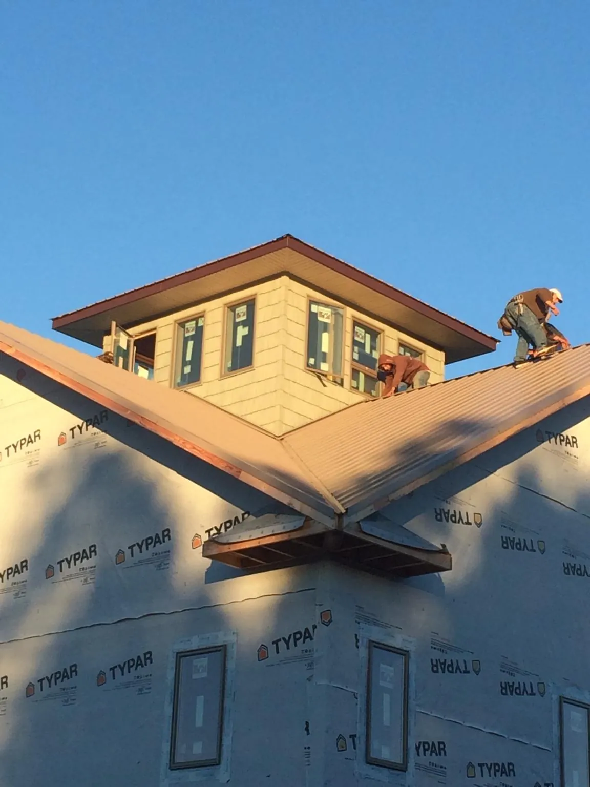 Roofers working around a rooftop cupola on a new metal roof at sunset — Roof Waterproofing in Red Creek by Roofing Brothers